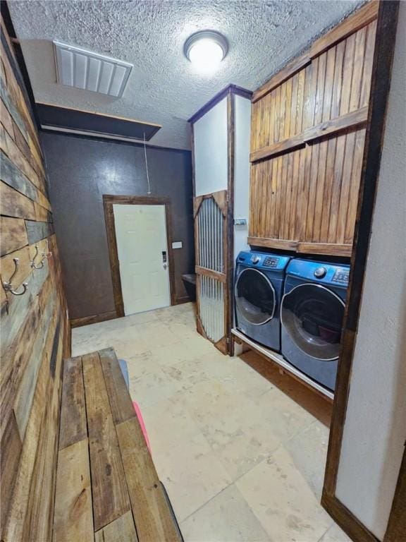 laundry room featuring washing machine and clothes dryer and a textured ceiling