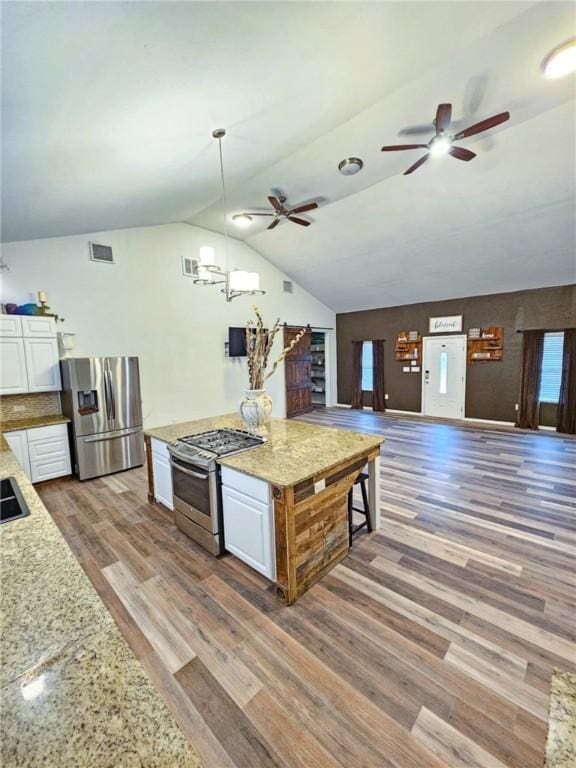 kitchen with white cabinetry, stainless steel appliances, light stone countertops, dark hardwood / wood-style flooring, and decorative light fixtures