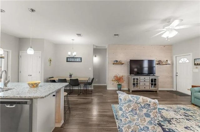 living room featuring ceiling fan with notable chandelier, sink, dark hardwood / wood-style floors, and wood walls