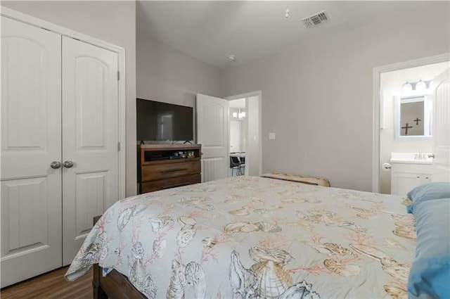 bedroom featuring a closet, wood-type flooring, and ensuite bath