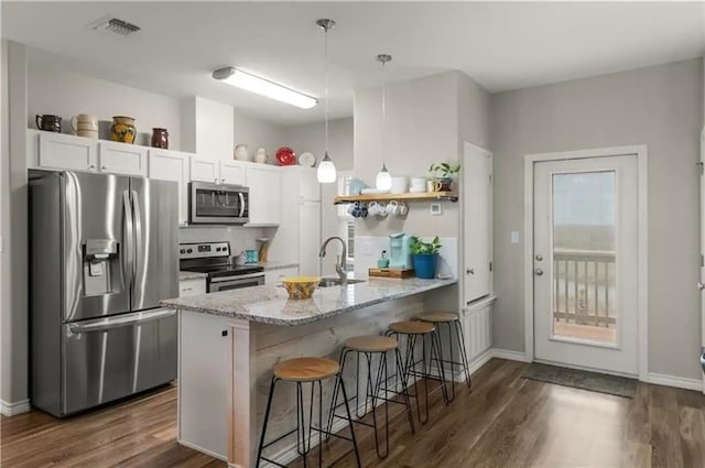 kitchen featuring white cabinetry, a breakfast bar area, stainless steel appliances, light stone counters, and sink