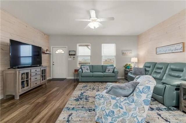 living room featuring ceiling fan, dark hardwood / wood-style flooring, and wood walls