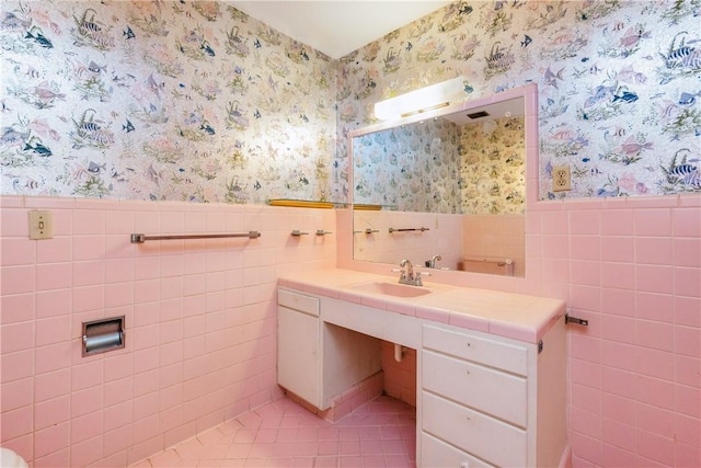 1325 S Whitney St, Aransas Pass, TX 78336 - bathroom with tile patterned floors, wallpapered walls, tile walls, a wainscoted wall, and vanity