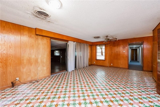 1325 S Whitney St, Aransas Pass, TX 78336 - empty room featuring wooden walls, a textured ceiling, ceiling fan, and tile patterned floors