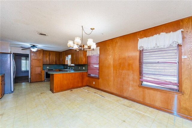 1325 S Whitney St, Aransas Pass, TX 78336 - kitchen featuring light floors, brown cabinetry, stainless steel appliances, a sink, and a peninsula
