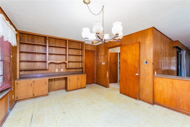 1325 S Whitney St, Aransas Pass, TX 78336 - unfurnished office featuring built in desk, an inviting chandelier, wooden walls, a textured ceiling, and light floors