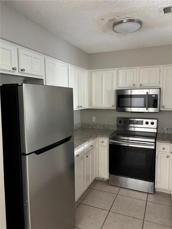 4401 River Valley Dr Unit 503, Corpus Christi, TX 78410 - kitchen featuring stainless steel appliances, a textured ceiling, white cabinetry, light tile patterned floors, and light stone countertops