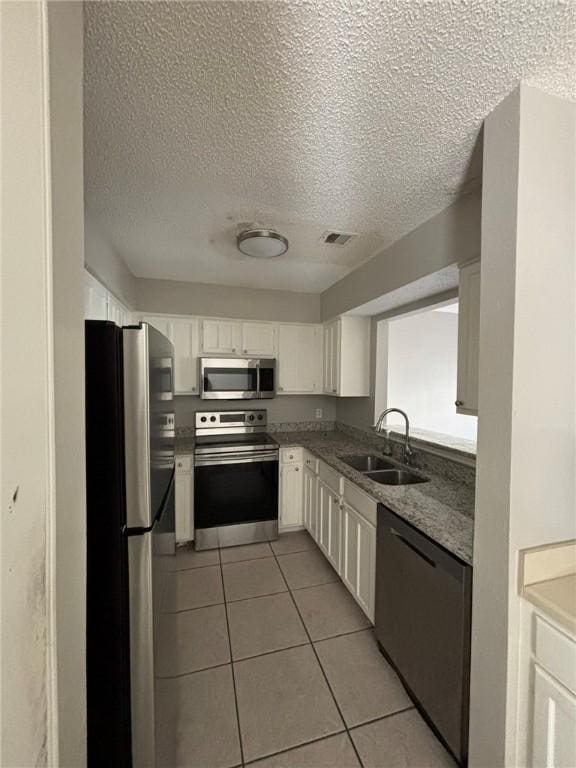 4401 River Valley Dr Unit 503, Corpus Christi, TX 78410 - kitchen featuring stainless steel appliances, a textured ceiling, light tile patterned floors, white cabinetry, and light stone counters