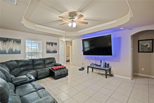 tiled living room with a tray ceiling, ceiling fan, and ornamental molding