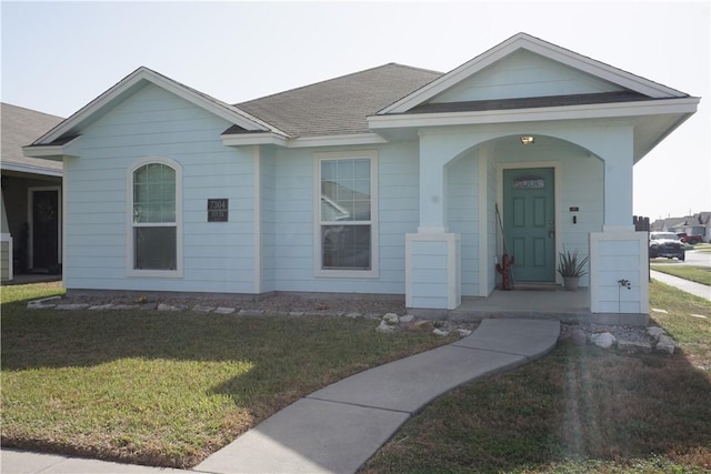 ranch-style home featuring roof with shingles and a front lawn