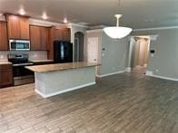 kitchen with stainless steel appliances, a kitchen island, dark hardwood / wood-style floors, and crown molding