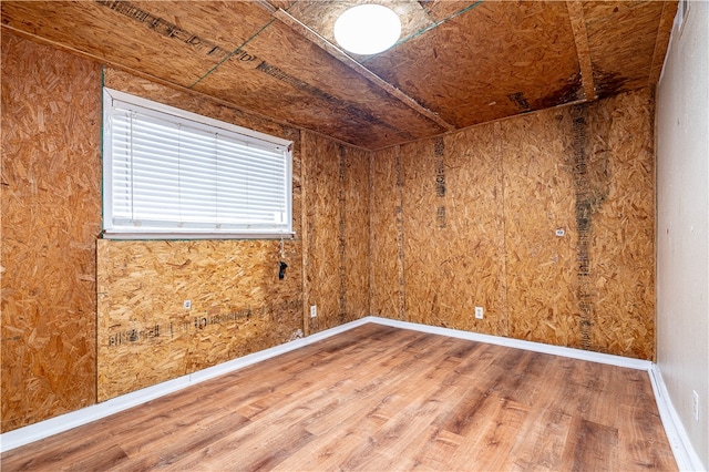 unfurnished room featuring hardwood / wood-style flooring and wooden walls