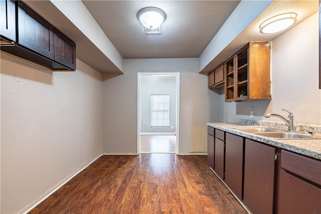 kitchen featuring dark brown cabinets, a textured ceiling, dark hardwood / wood-style floors, and sink