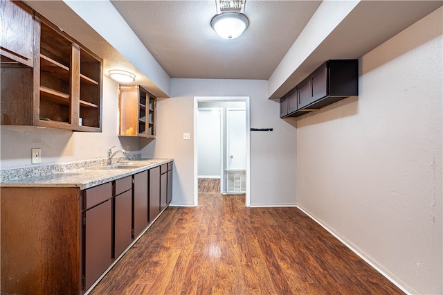 kitchen with a textured ceiling, dark brown cabinetry, dark hardwood / wood-style floors, and sink