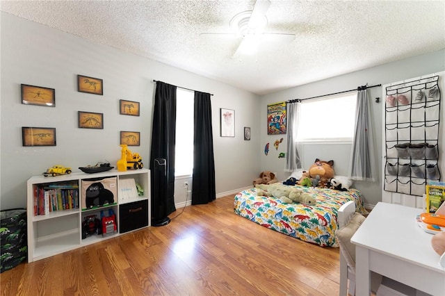 bedroom with ceiling fan, light hardwood / wood-style floors, and a textured ceiling