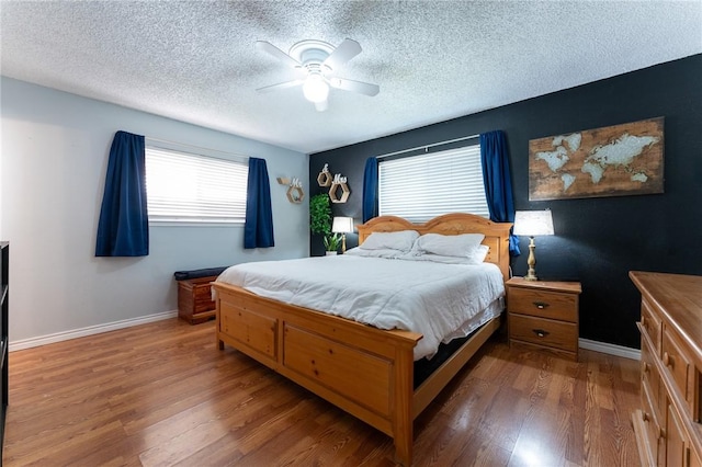 bedroom with ceiling fan, a textured ceiling, and dark hardwood / wood-style floors