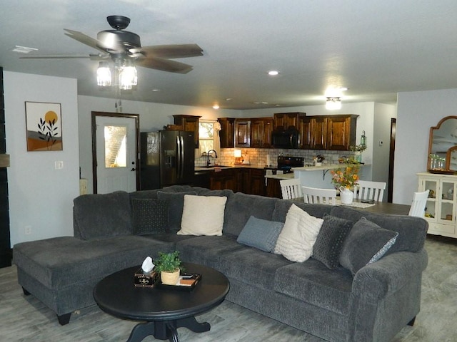 living room featuring ceiling fan, sink, and light hardwood / wood-style flooring