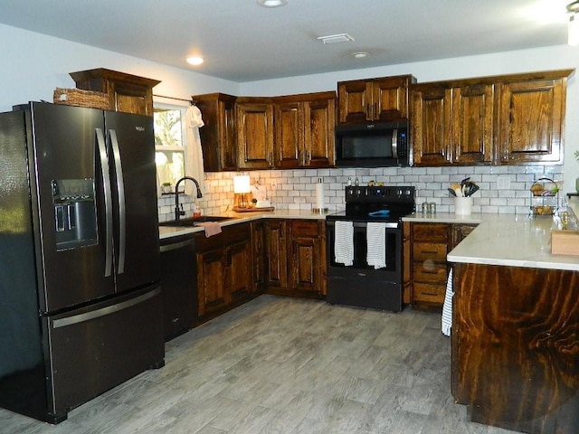 kitchen featuring tasteful backsplash, light wood-type flooring, sink, and black appliances