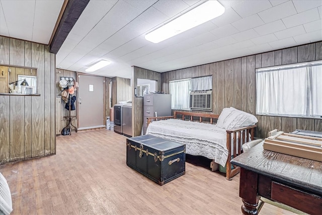 bedroom with wood walls, multiple windows, washer / clothes dryer, and light hardwood / wood-style flooring