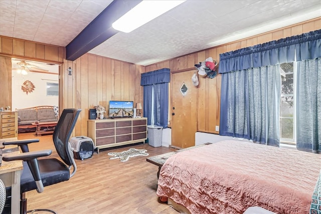 bedroom with hardwood / wood-style floors, wood walls, and beamed ceiling