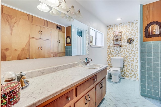 bathroom with toilet, vanity, tile patterned flooring, and tile walls