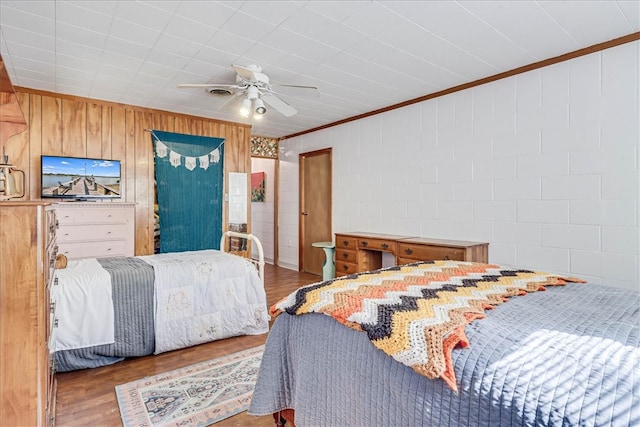 bedroom with ceiling fan, wooden walls, light hardwood / wood-style flooring, and ornamental molding