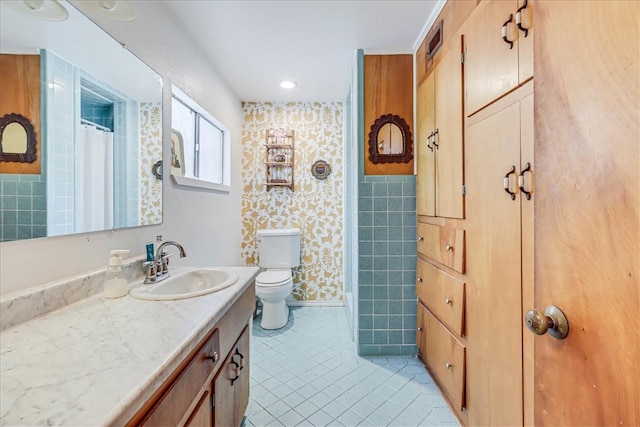 bathroom featuring vanity, tile patterned flooring, toilet, and tile walls