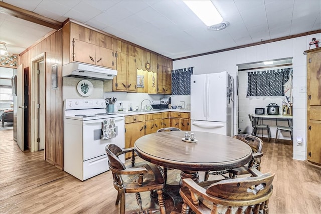 kitchen with wood walls, sink, ornamental molding, white appliances, and light hardwood / wood-style flooring