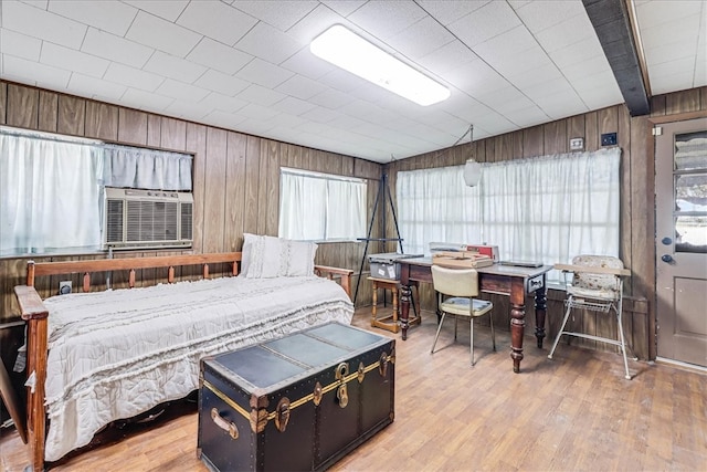 bedroom featuring wood walls, wood-type flooring, and multiple windows