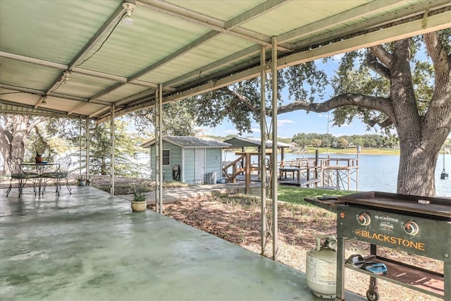 view of patio / terrace featuring a dock, a shed, and a water view