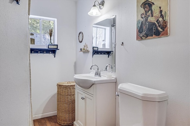 bathroom featuring toilet, vanity, and hardwood / wood-style floors