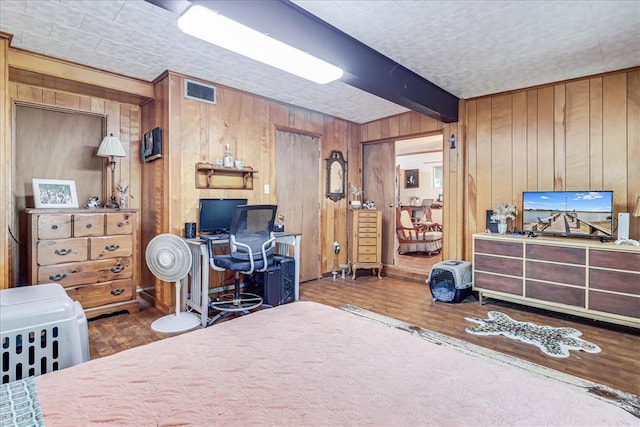 bedroom featuring wooden walls, hardwood / wood-style flooring, and beam ceiling