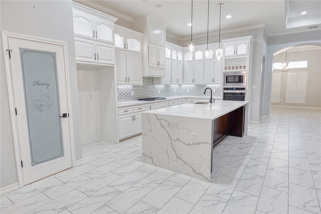 kitchen featuring light stone countertops, a center island with sink, white cabinets, and stainless steel appliances