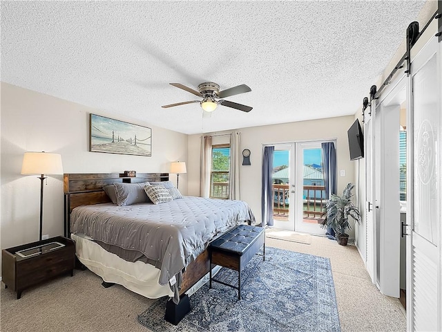 bedroom featuring a textured ceiling, access to exterior, ceiling fan, and a barn door