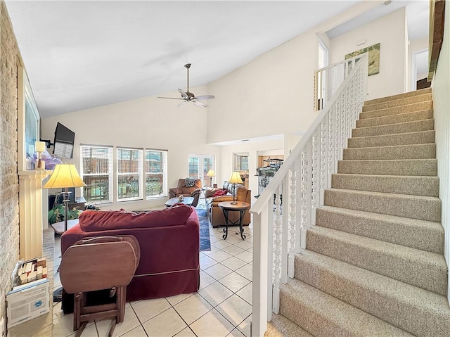living room featuring high vaulted ceiling, light tile patterned floors, a fireplace, a ceiling fan, and stairway