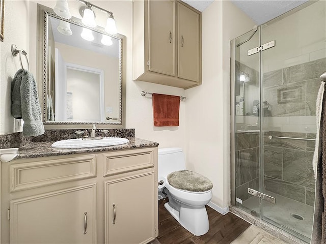 bathroom with a shower stall, vanity, toilet, and wood finished floors