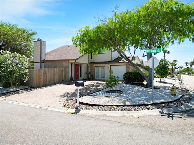 view of front of home with french doors, an attached garage, fence, and driveway
