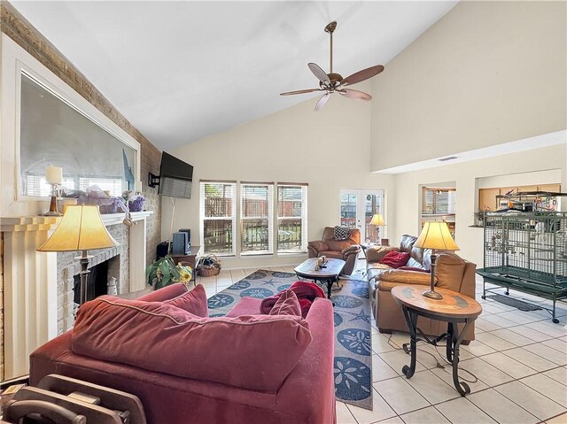 living area with high vaulted ceiling, light tile patterned floors, ceiling fan, a fireplace, and visible vents