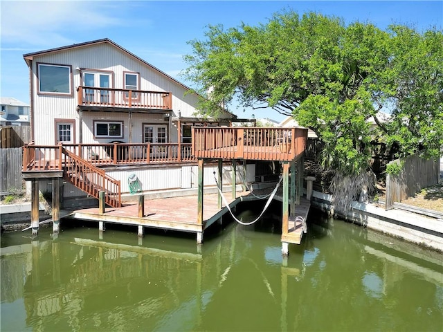 view of dock featuring boat lift, fence, stairway, a balcony, and a deck with water view