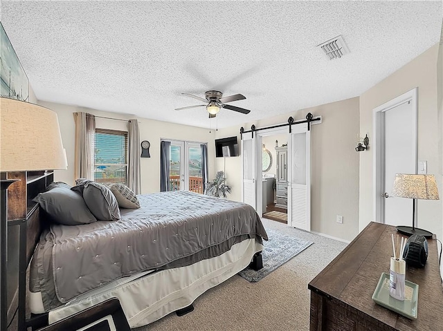 carpeted bedroom featuring access to outside, a textured ceiling, visible vents, and a barn door