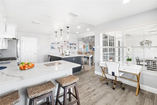 kitchen featuring freestanding refrigerator, visible vents, light wood-style flooring, and a peninsula