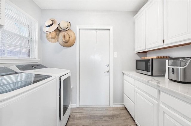 laundry room featuring light wood-style floors, cabinet space, and separate washer and dryer