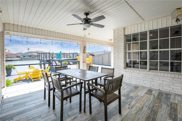 wooden terrace featuring a water view, ceiling fan, and outdoor dining area