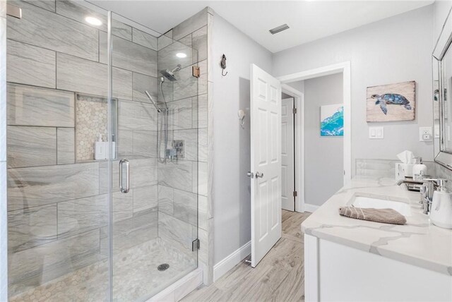 full bath with a stall shower, baseboards, visible vents, and a sink