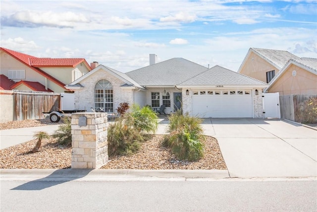 view of front of property with a wall unit AC, an attached garage, fence, concrete driveway, and a gate