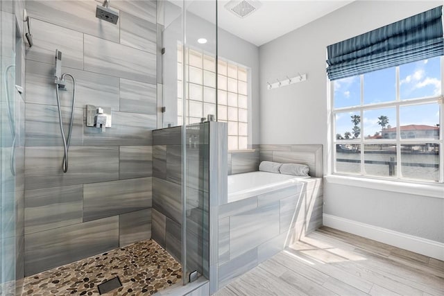 full bath with a garden tub, visible vents, a stall shower, wood finished floors, and baseboards