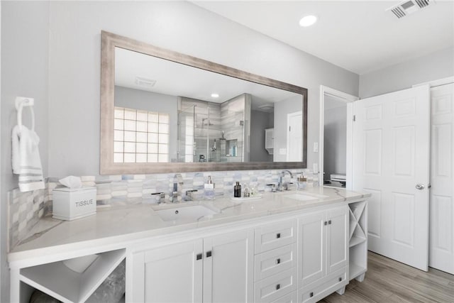 bathroom featuring a shower stall, visible vents, backsplash, and a sink