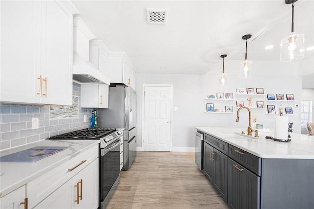 kitchen with stainless steel appliances, a sink, visible vents, white cabinetry, and custom range hood