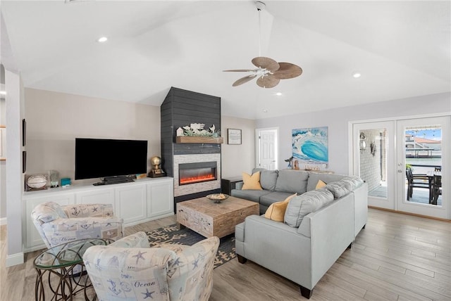 living area featuring vaulted ceiling, recessed lighting, a fireplace, and light wood-style floors