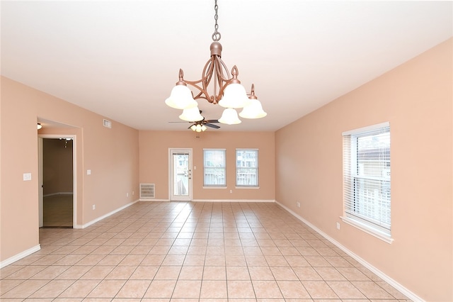 tiled empty room featuring a chandelier and a wealth of natural light